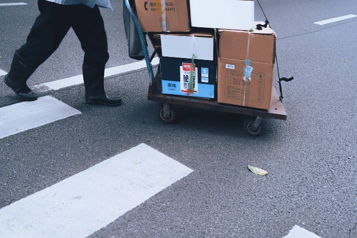 Person pulls a cart with boxes across a crosswalk.